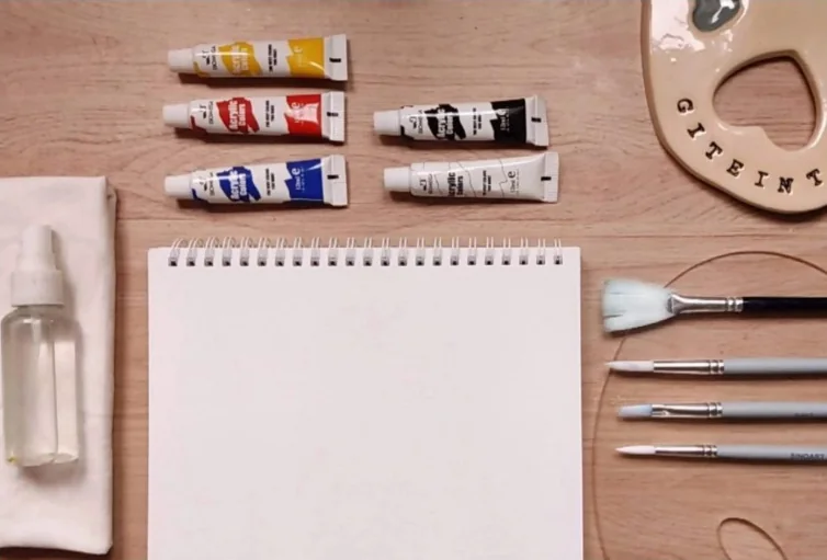 Acrílicos, pinceles, paleta y cuaderno listos para pintar