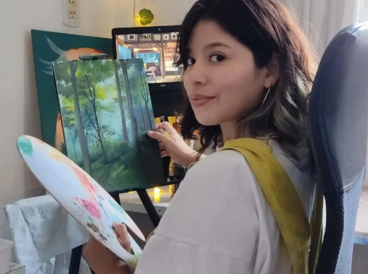 Gisela Guiralde con su paleta, frente a un paisaje de bosque