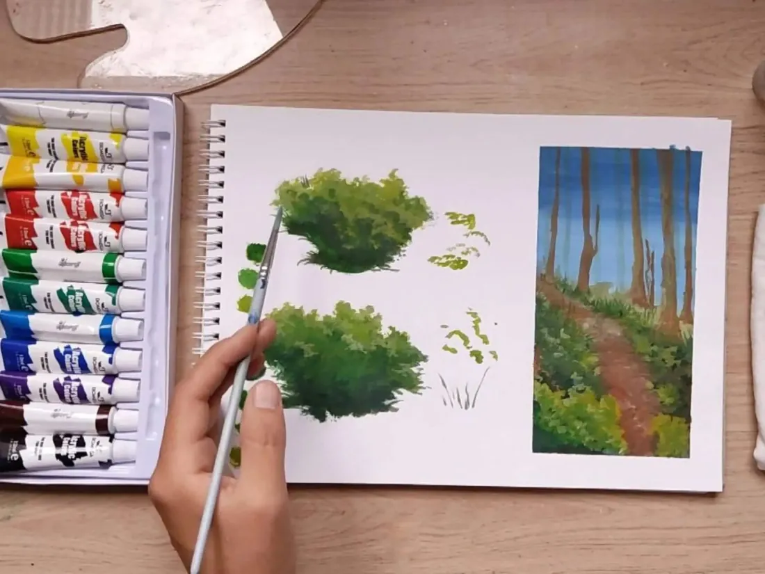 Mano pintando arbustos en un cuaderno